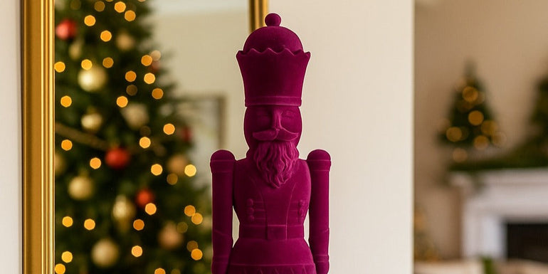 Figurină spărgător de nuci mov catifelat așezată pe un bufet de lemn, negru, decorat de Crăciun