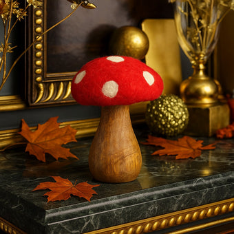 Ciupercă decorativă din lemn cu pălărie roșie și buline albe, așezată pe un bufet cu blat din marmură verde, decorat de toamnă