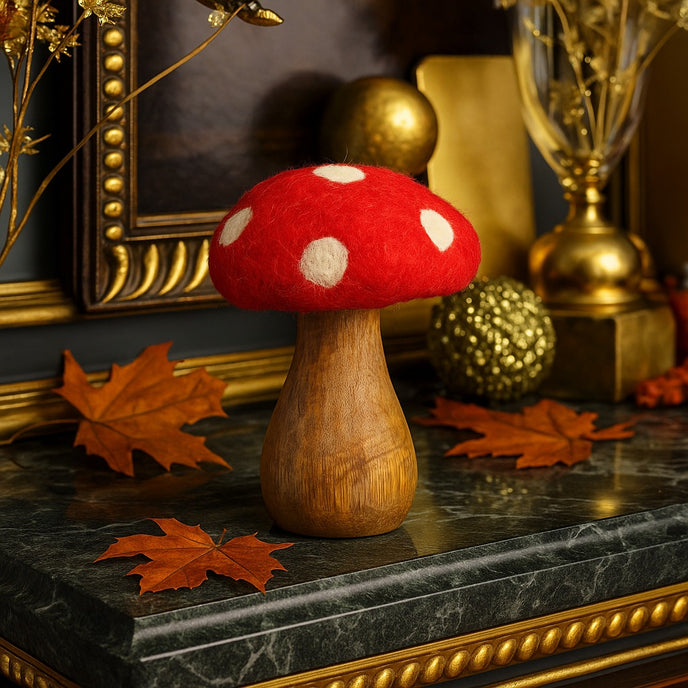 Ciupercă decorativă din lemn cu pălărie roșie și buline albe, așezată pe un bufet cu blat din marmură verde, decorat de toamnă