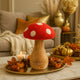 Ciupercă decorativă din lemn cu pălărie roșie și buline albe, așezată pe o tavă aurie, decorată de toamnă