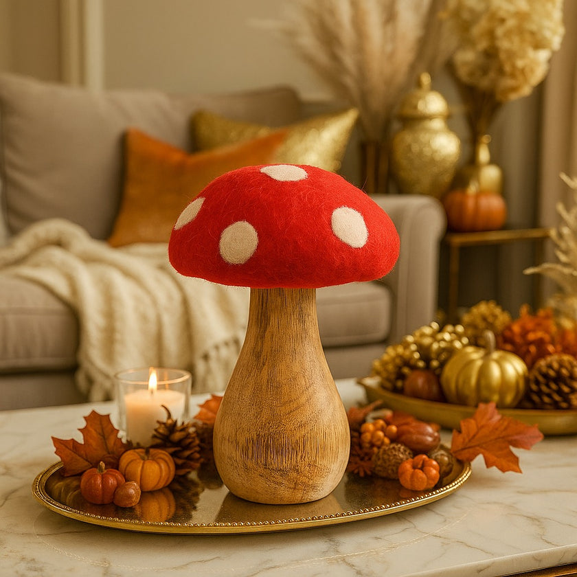 Ciupercă decorativă din lemn cu pălărie roșie și buline albe, așezată pe o tavă aurie, decorată de toamnă