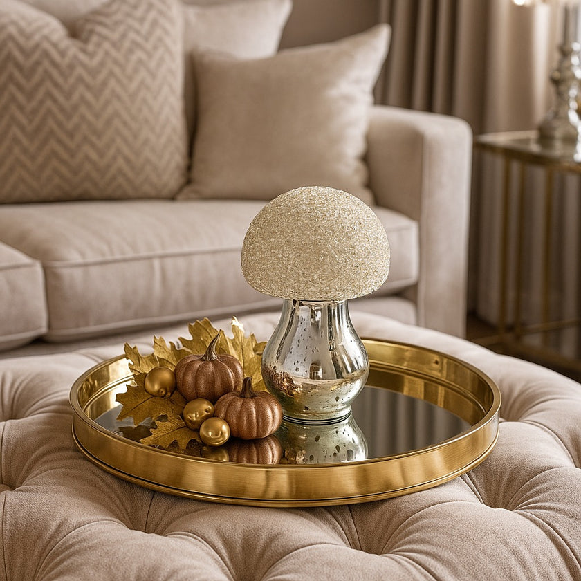 Ciupercă decorativă din sticlă, de culoare argintie și pălărie cu paiete albe, așezată pe o tava metalică, decorată de toamnă