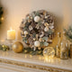 Coroniță de Crăciun cu conuri de brad și globuri albe agățată pe o poliță de lemn alb cu auriu, decorată de Crăciun