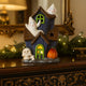 Decorațiune de Halloween în formă de casă bântuită cu fantome și lumină led, așezată pe un bufet de lemn, decorat de Halloween