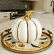 Dovleac decorativ alb cu codiță aurie pentru toamnă așezat pe o tavă aurie cu motive de Halloween. Tava este așezată pe un blat alb in bucătărie