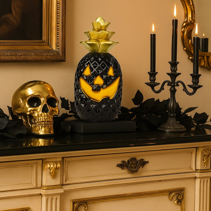 Dovleac decorativ pentru Halloween, în culori negru și auriu, cu led, așezat pe un bufet cu blat negru, decorat de Halloween