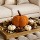 Dovleac decorativ din material textile, croșetat, de culoare portocalie, așezat pe o tavă aurie, decorată de toamnă