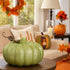 Dovleac decorativ verde cu sclipici așezat pe o masă, într-un living decorat de toamnă
