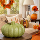 Dovleac decorativ verde cu sclipici așezat pe o masă, într-un living decorat de toamnă
