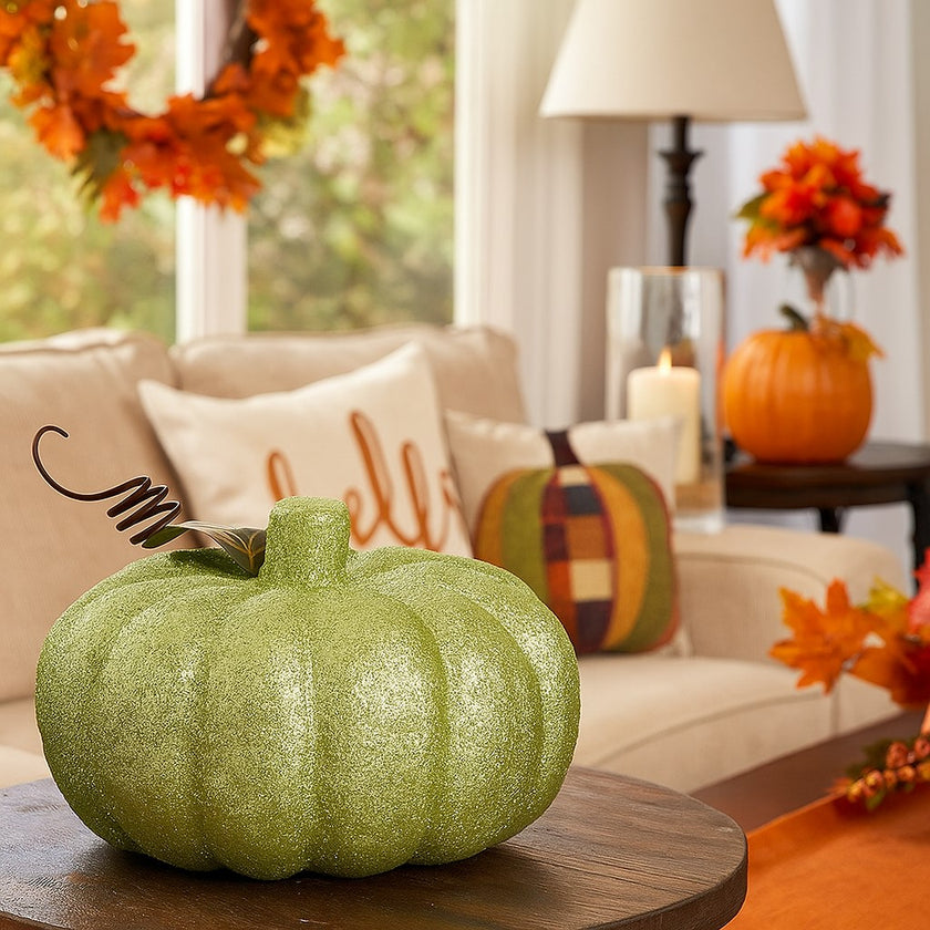Dovleac decorativ verde cu sclipici așezat pe o masă, într-un living decorat de toamnă