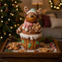 Figurină decorativă de Crăciun, ren din turtă dulce în formă de brioșă așezată pe o tavă din lemn, decorată cu biscuiți de turtă dulce și zăpadă artificială