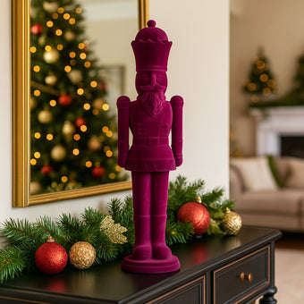 Figurină spărgător de nuci mov catifelat așezată pe un bufet de lemn, negru, decorat de Crăciun