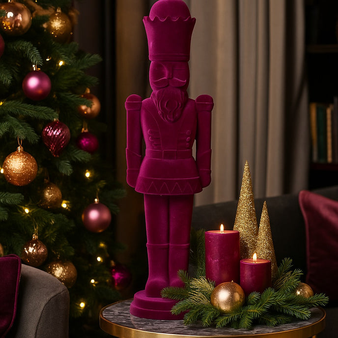 Figurină spărgător de nuci mov catifelat așezată pe o masă rotundă, cu blat de marmură gri, decorată de Crăciun