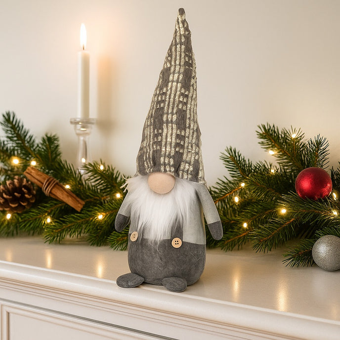 Gnom decorativ de Crăciun cu pălărie lungă gri așezat pe un bufet de lemn alb, decorat de Crăciun 