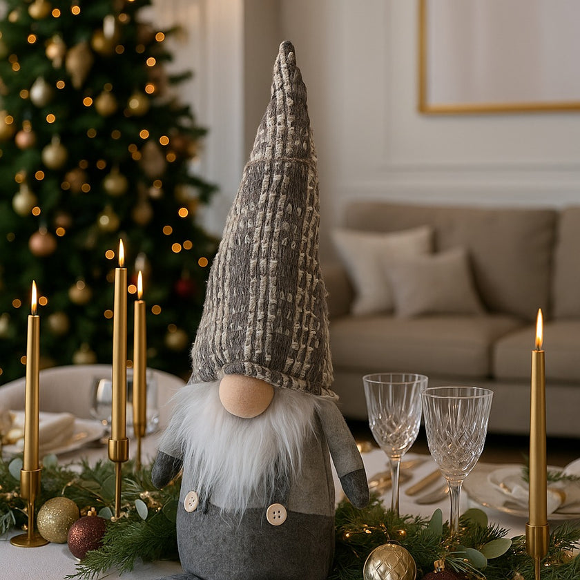 Gnom decorativ de Crăciun cu pălărie lungă gri așezat pe o masă festivă decorată de Crăciun