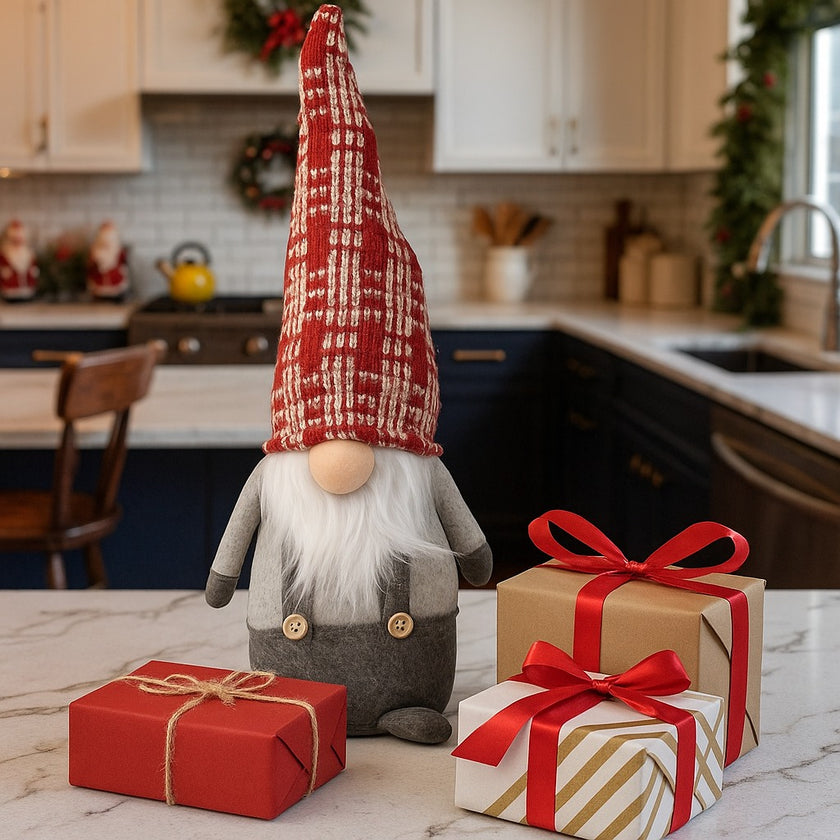 Gnom decorativ de Crăciun cu pălărie lungă roșie așezat pe un blat alb de bucătărie, lângă 3 cadouri de Crăciun