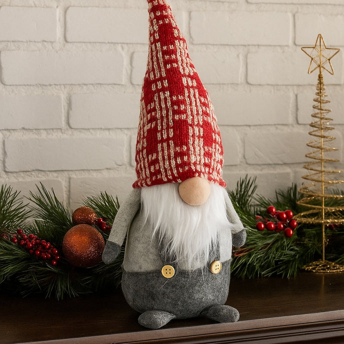 Gnom decorativ de Crăciun cu pălărie lungă roșie așezat pe un bufet de lemn maro, decorat de Crăciun