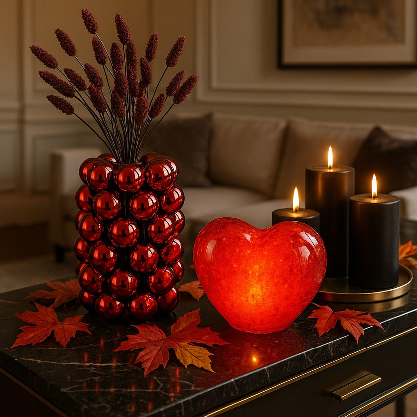 Inimă decorativă din sticlă de culoare roșie, cu lumină led, așezată pe bufet cu blat de piatră neagră, decorat de toamnă