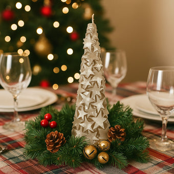 Lumânare în formă de brad auriu cu stele și sclipici așezată în mijlocul unei coronițe de brad, pe o masă festivă de Crăciun