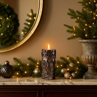 Lumânare cilindrică decorativă cu stele și sclipici Crăciun așezată pe un bufet de marmură decorat de Crăciun