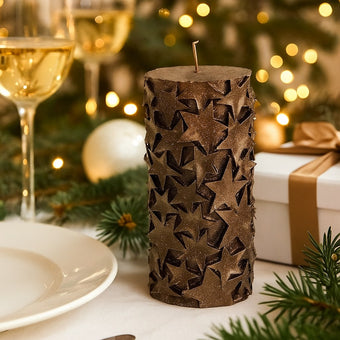 Lumânare cilindrică decorativă cu stele și sclipici Crăciun așezată pe masă festivă decorată de Crăciun