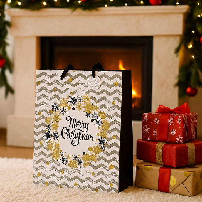 Pungă cadou de Crăciun, cu model zig-zag în alb și gri, cu fulgi aurii, asezată pe un covor, in fața unui șemineu decorat de Crăciun