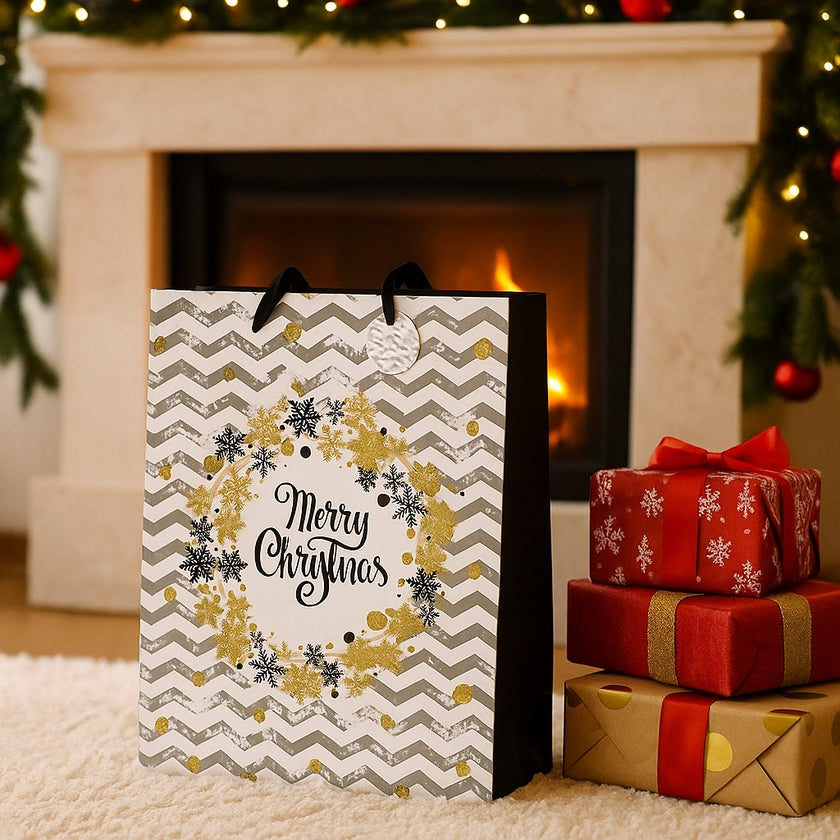 Pungă cadou de Crăciun, cu model zig-zag în alb și gri, cu fulgi aurii, asezată pe un covor, in fața unui șemineu decorat de Crăciun