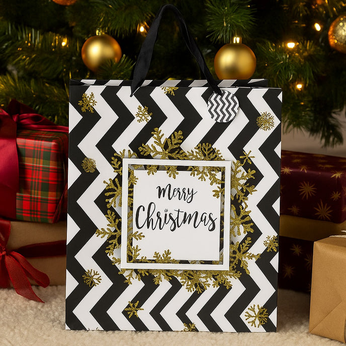 Pungă cadou de Crăciun, cu model zig-zag în alb și negru, cu fulgi aurii, asezată pe covor, sub un brad decorat de Crăciun
