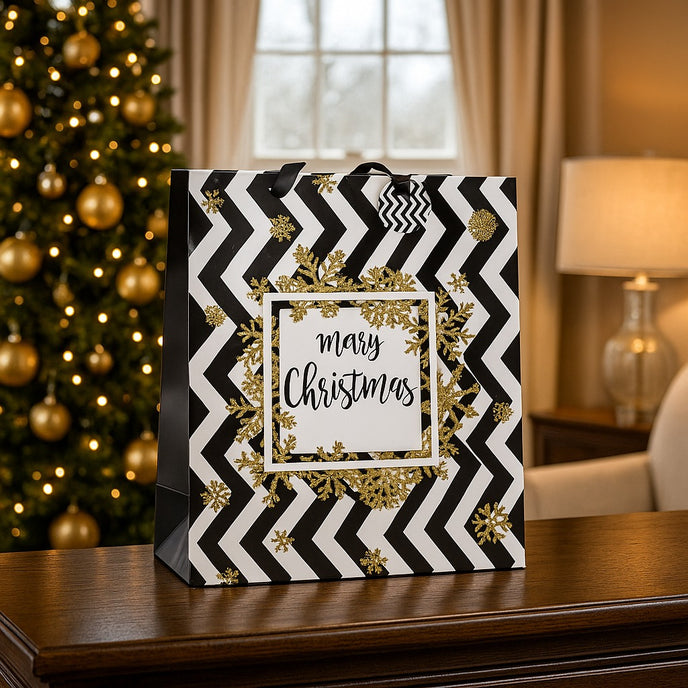 Pungă cadou de Crăciun, cu model zig-zag în alb și negru, cu fulgi aurii, asezată pe un bufet de lemn maro, în fața unui brad decorat de Crăciun