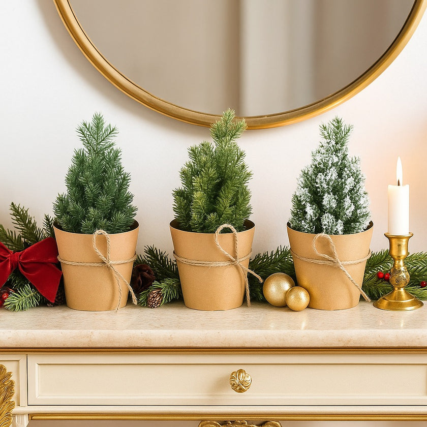 Set 3 brazi decorativi de Crăciun, în ghiveci de hârtie, asezați pe un bufet alb cu auriu și blat de marmură, decorat de Crăciun