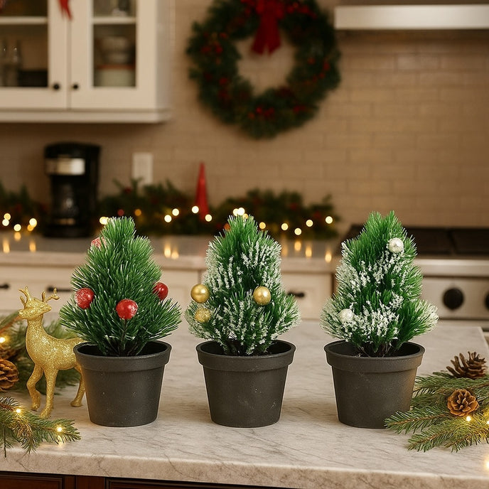 Set 3 brazi decorativi cu globuri, în ghiveci negru, așezate pe un blat alb de bucătărie, decorată de Crăciun