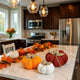 Set de 3 dovleci decorative, textile, de culoare portocaliu roșu și alb, așezați pe un blat alb de bucătărie, decorat de toamnă