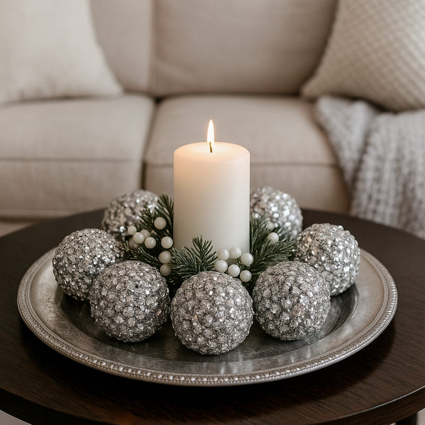 Set globuri argintii de Crăciun cu cristale, așezate pe o tava metalică argintie,cu o lumânare aprinsă in mijloc. Tava se află pe o masă rotundă de lemn