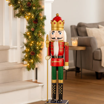 Spărgător de nuci roșu și verde cu coroană și sceptru așezat lângă scară în living decorată de Crăciun