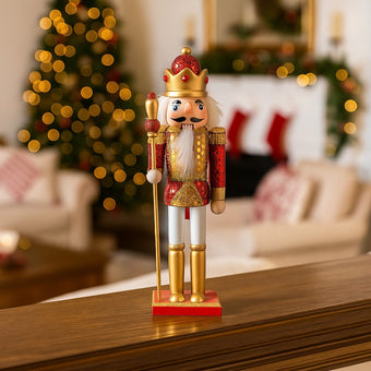 Spărgător de nuci roșu și auriu așezat pe un bufet maro, într-un living decorat de Crăciun