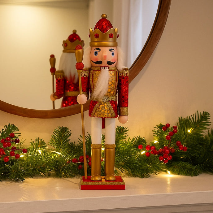 Spărgător de nuci roșu și auriu așezat pe o manta de șemineu albă, decorată de Crăciun