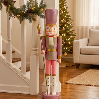 Spărgător de nuci roz cu sclipici și sceptru auriu așezat lângă o scară din living, decorată de Crăciun