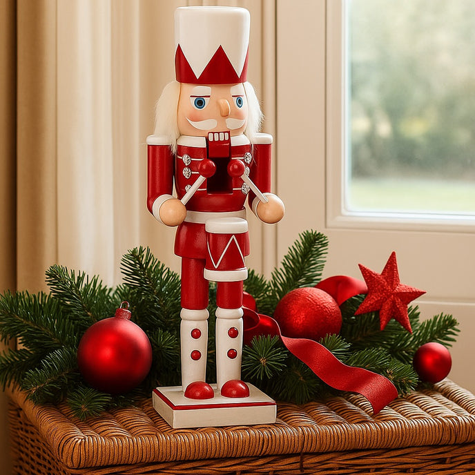 Spărgător de nuci toboșar alb și roșu așezat pe o ladă de răchita decorată de Crăciun