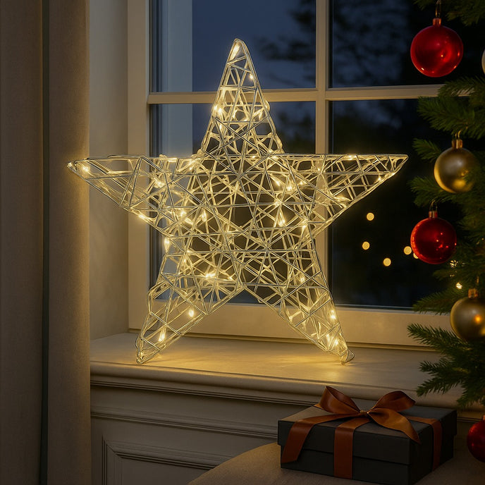 Stea decorativă argintie cu leduri aprinse, așezată pe un pervaz de lemn alb, decorat de Crăciun