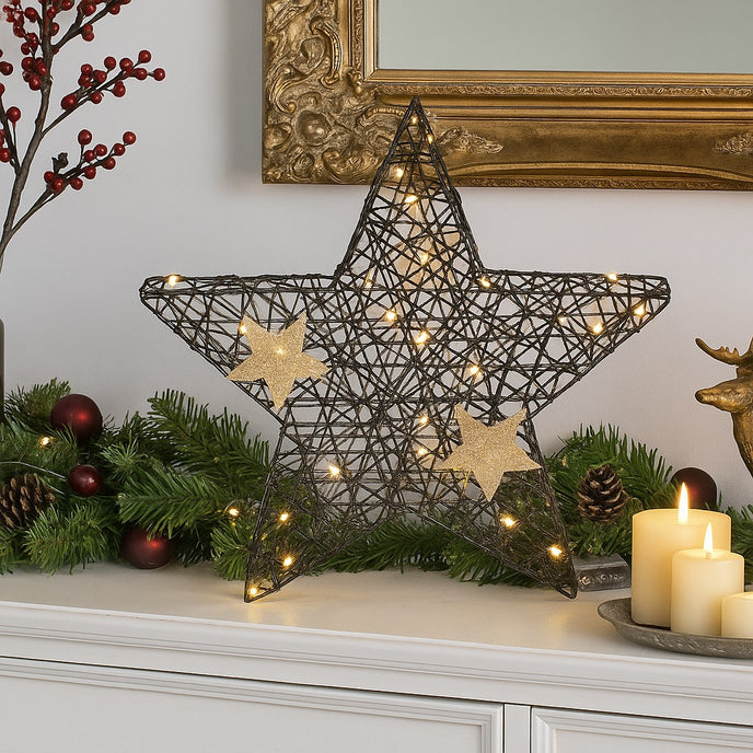 Stea decorativă neagră cu leduri aprinse, așezată pe un bufet de lemn alb, decorat de Crăciun