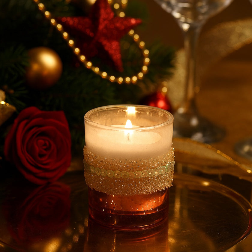 Suport de lumânare din sticlă roz, cu paiete, aprins, pe o tavă aurie