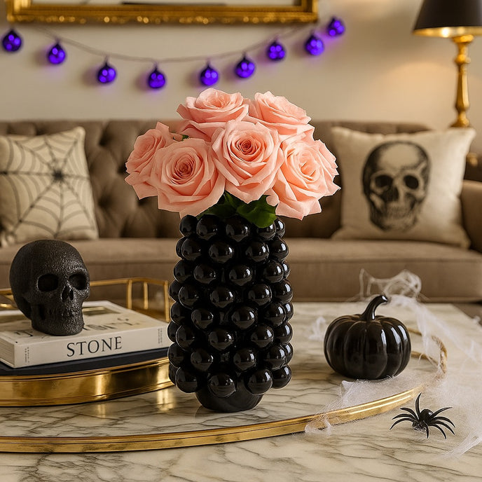 Vază decorativă negru lucios, cu model în formă de bubble și un buchet de flori în ea, așezată pe o masă cu blat de marmură, decorată de Halooween