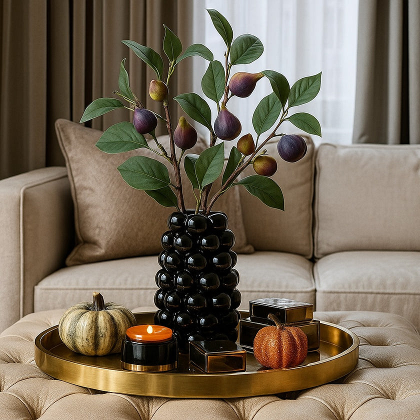 Vază decorativă negru lucios, cu model în formă de bubble și un buchet de flori în ea, așezată pe o tavă rotundă, aurie decorată de toamnă