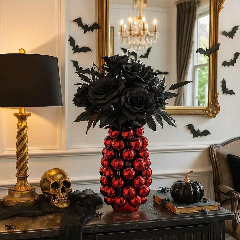 Vază decorativă roșu lucios, cu model în formă de bubble și un buchet de flori în ea, așezată pe un bufet cu blat de marmură neagră, decorat de Halloween