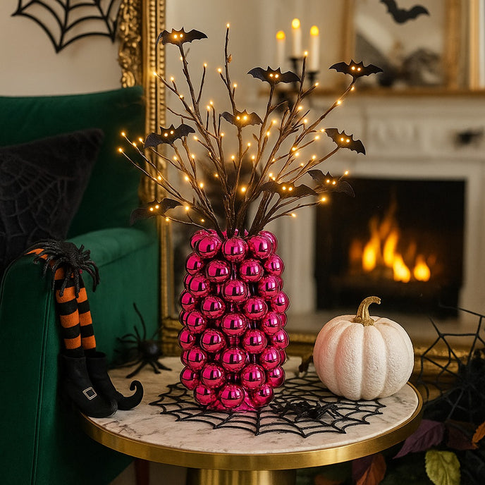 Vază decorativă roz lucios, cu model în formă de bubble și un buchet de flori în ea, așezată pe o masă rotundă, decorată de Halloween