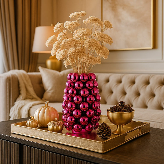 Vază decorativă roz lucios, cu model în formă de bubble și un buchet de flori în ea, așezată pe o tavă aurie, deocrată de toamnă