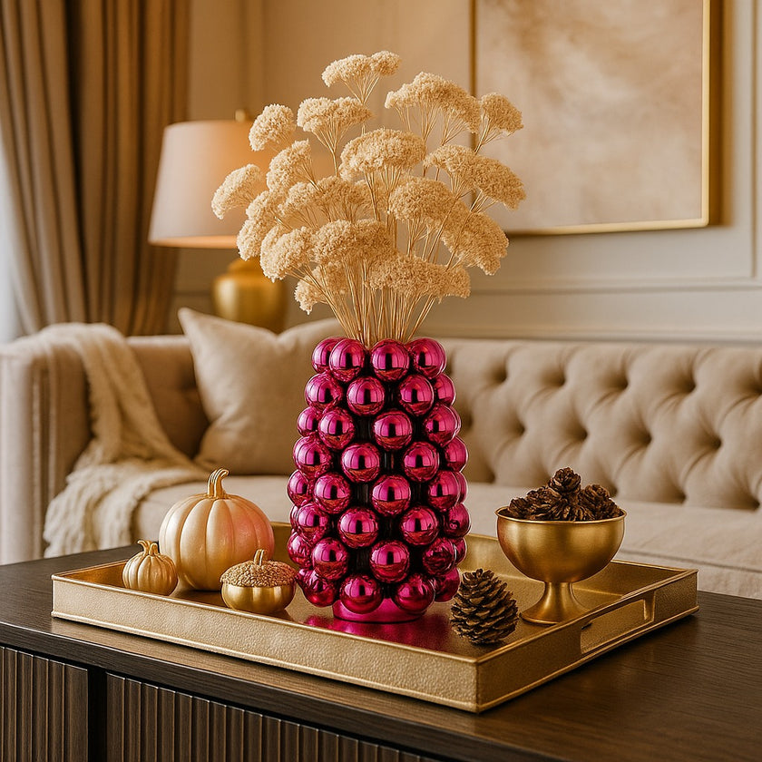 Vază decorativă roz lucios, cu model în formă de bubble și un buchet de flori în ea, așezată pe o tavă aurie, deocrată de toamnă